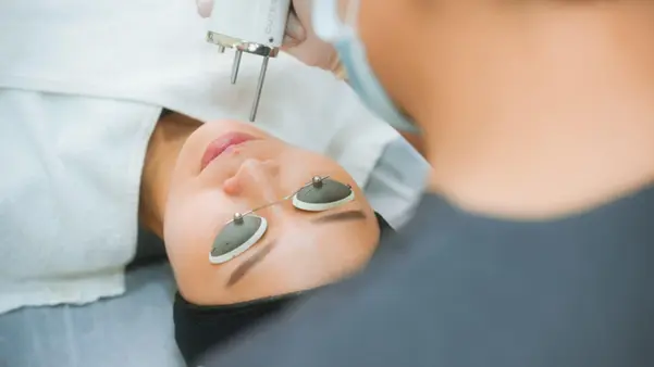 A professional cosmetologist performing a Pico laser treatment on a patient's face to target pigmentation and acne scars.