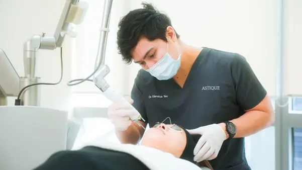 A skilled doctor at Astique Clinic standing next to modern Pico laser medical equipment, ready to perform a safe and gentle skin treatment.