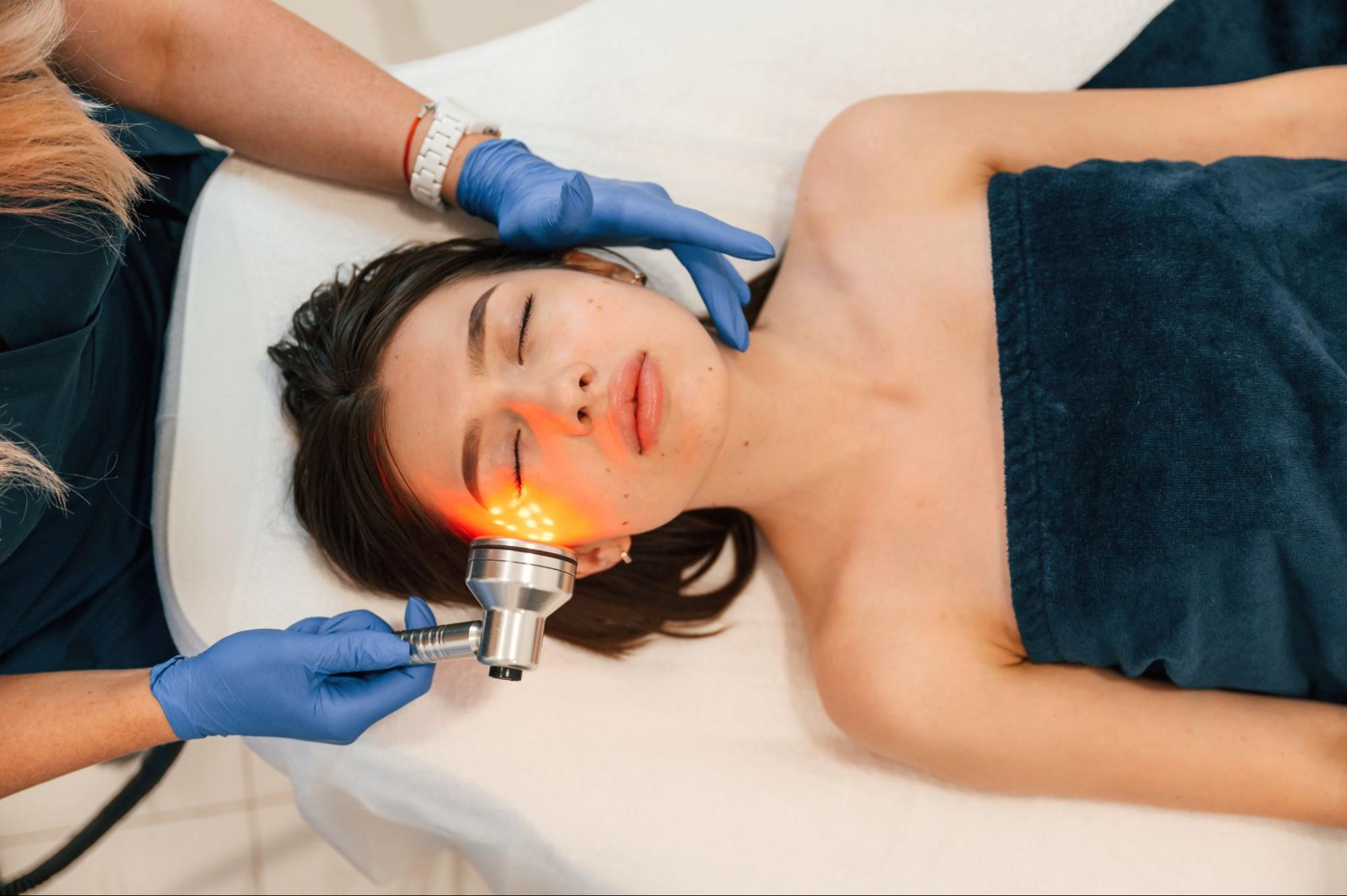 A professional aesthetician performing a radiofrequency skin tightening treatment on a patient's cheek. A professional aesthetician performing a radiofrequency skin tightening treatment on a patient's cheek.